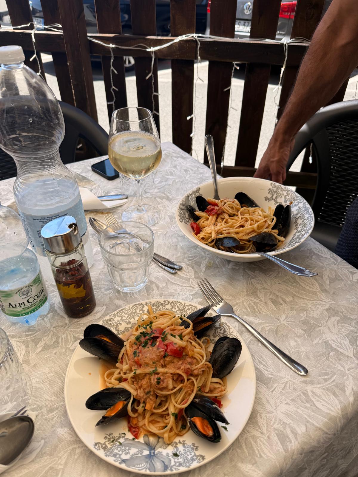 Tavolo sul dehors con linguine ai frutti di mare e vino bianco